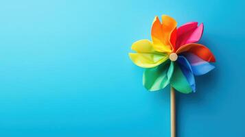 Brightly colored pinwheel spins gently against a solid blue background on a sunny day photo