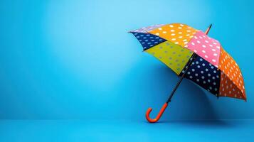 Colorful polka dot umbrella leaning against bright blue background in bright indoor setting photo