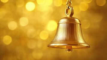 Golden bell hanging against a shimmering golden background during festive celebrations photo