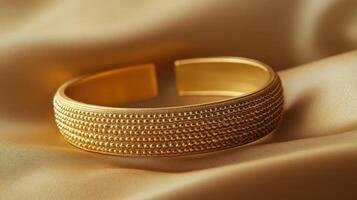 Elegant gold cuff bracelet with intricate design displayed on soft fabric photo