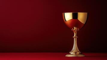 Elegant golden chalice displayed against a deep red background in a dimly lit setting highlighting its intricate details and craftsmanship photo