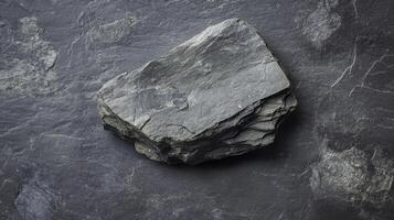 Natural gray rock resting on a dark surface showcasing texture and geological features photo