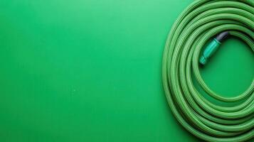 Green garden hose coiled on a bright green background enhancing an outdoor setting photo
