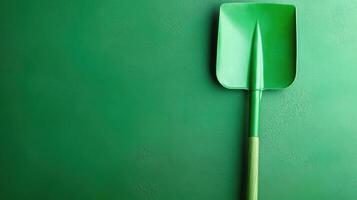 Bright green gardening shovel resting against a vibrant green wall in a gardening space photo