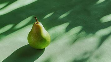 Green pear resting on a textured surface casting soft shadows in natural light photo