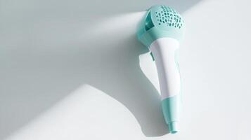 Small turquoise hair dryer resting on a light surface in a well-lit room photo