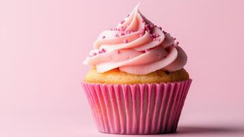 A cupcake with pink frosting on a pink background photo