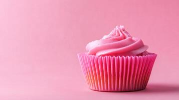 A cupcake with pink frosting on a pink background photo