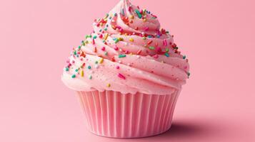 A cupcake with pink frosting and sprinkles on a pink background photo