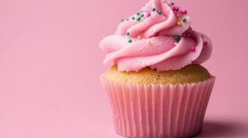 A cupcake with pink frosting on a pink background photo