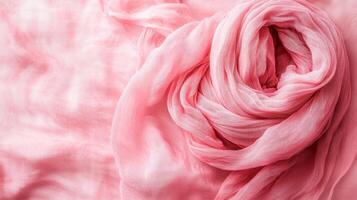 Delicate pink scarf elegantly arranged on a soft textured background, showcasing its lightweight fabric and gentle hues photo