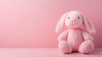 Cute pink bunny plush toy sitting against a soft pink background in a whimsical setting photo