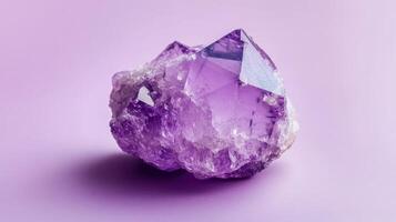 Beautiful amethyst crystal displaying rich purple hues against a soft pink background in natural light photo