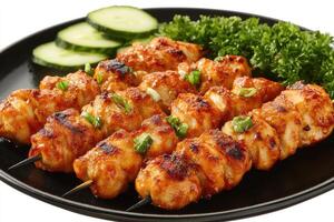 Grilled chicken skewers with garnish on black plate photo