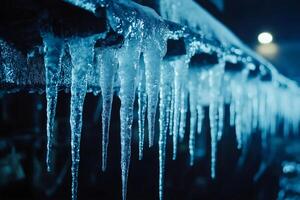 Sharp icicles hanging from roof at night during winter season photo