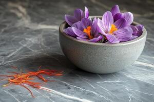Saffron stigmas and crocus flowers resting in a bowl on a marble table photo