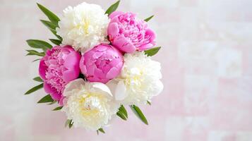 Fresh Pink and White Peonies with Green Leaves in a Vase Arrangement photo