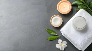 Relaxing Spa Setup with Candles, Cream, Towel and Green Leaves photo