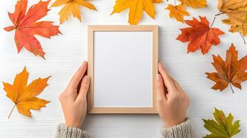 Hands Holding Blank Frame Surrounded by Colorful Autumn Leaves photo