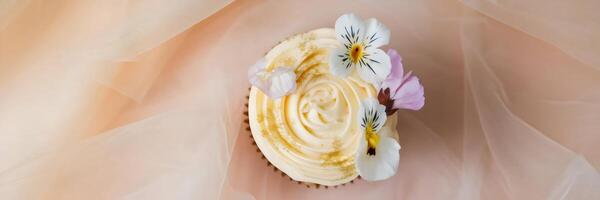 Flat lay of an elegant cupcake with buttercream frosting and edible flowers photo
