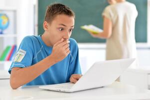 Portrait of boy studing with laptop at classroom photo