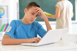 Portrait of boy studing with laptop at classroom photo