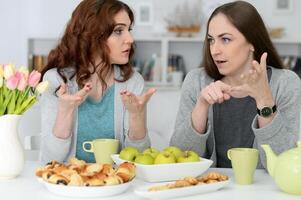 Two best friends eating while sitting at the table together photo