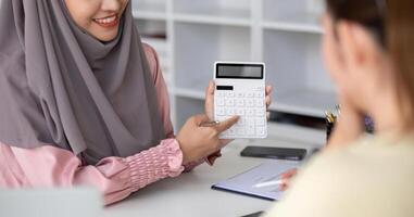 Muslim business woman calculates numbers Calculate profits and taxes for customers with a calculator. photo