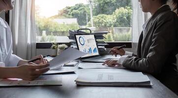 Close-up, A team of accountants and businesswomen sit and work on numbers and graphs. On the laptop on the table in the office photo