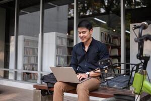A young Asian businessman rides a bicycle to work. Use a reusable water bottle. Working outside of the office using a laptop The concept of saving energy and reducing pollution to the environment. photo