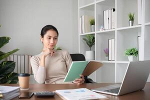 Young Asian student studies online about graphs and statistics. Happy Zoom call studying with laptop computer photo
