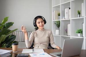 Young Asian student studies online about graphs and statistics. Happy Zoom call studying with laptop computer photo