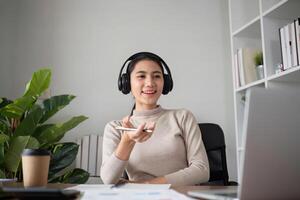 Young Asian student studies online about graphs and statistics. Happy Zoom call studying with laptop computer photo