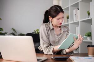 Young Asian student studies online about graphs and statistics. Happy Zoom call studying with laptop computer photo