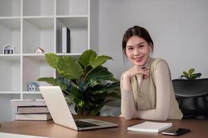 Asian college student sit at home studying online using a calling program on their laptop. photo