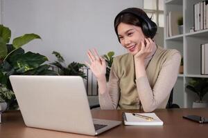 Asian college student sit at home studying online using a calling program on their laptop. photo