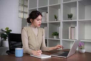 Asian college student who is bored Sitting in front of a laptop studying online through a calling program on a laptop at home. photo