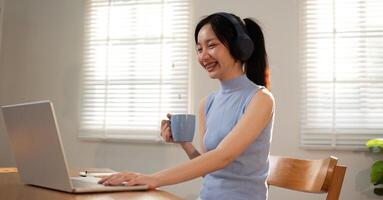Asian college student sit at home studying online using a calling program on their laptop. photo