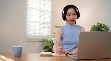 Asian college student sit at home studying online using a calling program on their laptop. photo