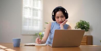 Asian college student who is bored Sitting in front of a laptop studying online through a calling program on a laptop at home. photo
