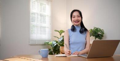 Asian college student sit at home studying online using a calling program on their laptop. photo
