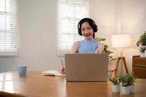 Asian college student sit at home studying online using a calling program on their laptop. photo