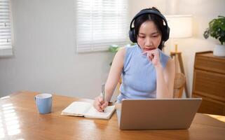 Asian college student who is bored Sitting in front of a laptop studying online through a calling program on a laptop at home. photo