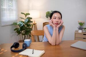 Asian college student who is bored Sitting in front of a laptop studying online through a calling program on a laptop at home. photo