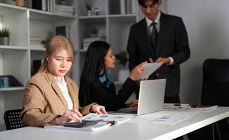 Diverse Business Team Collaborating on Work Plans in Modern Office Setting with Laptops and Documents photo