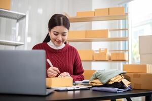 SME business entrepreneurs small in asia Write shipping information on a cardboard box in my home office. Small business operators preparing to ship to customers photo