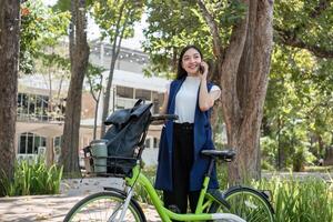 Confident Businesswoman Commuting to Work on Bicycle in Urban Environment Surrounded by Nature and Modern Architecture photo