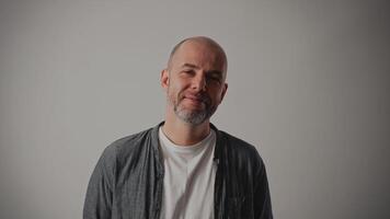 A middle-aged man stands against a white background. He has a kind expression on his face and a gentle smile, looking directly at the camera. His face reflects warmth and positive human emotions. video