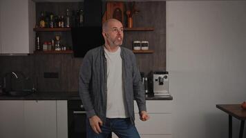 A very angry and furious middle-aged man in his kitchen. The man is visibly enraged, with an angry expression on his face and sharp gestures. His mood is filled with anger video
