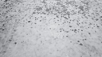 An animation of gray and black raindrops forming circular patterns on a white concrete road creating unique abstract designs with a calming effect reminiscent of yin-yang energy video